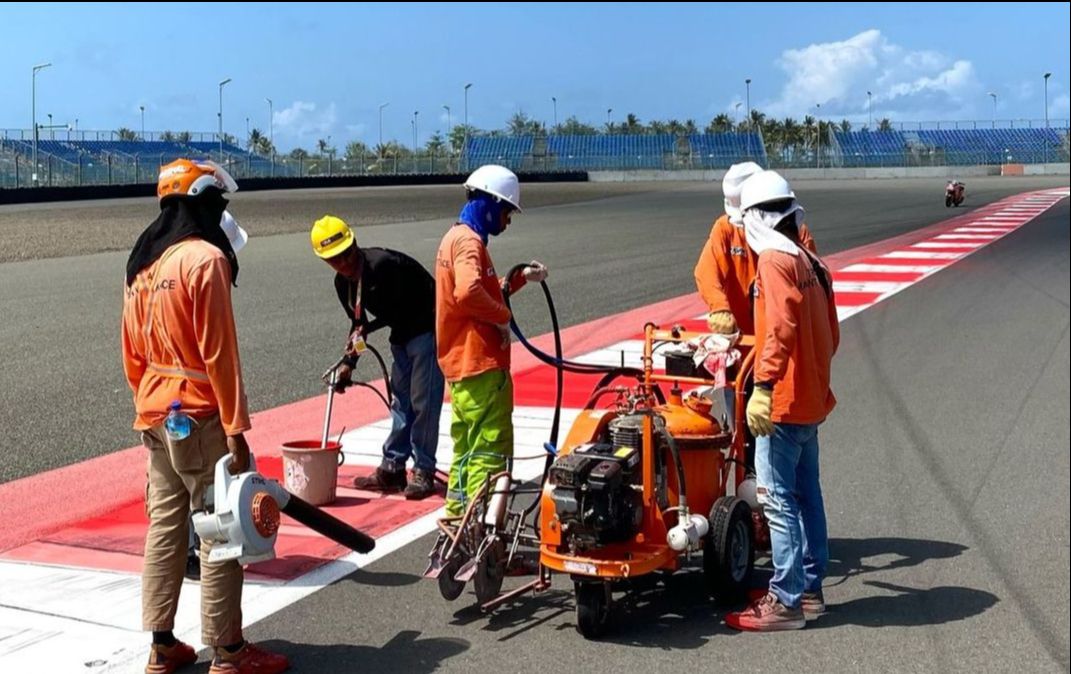 Petugas Sirkuit Mandalika mengecat ulang aspal bagian pinggir lintasan (themandalikagp)